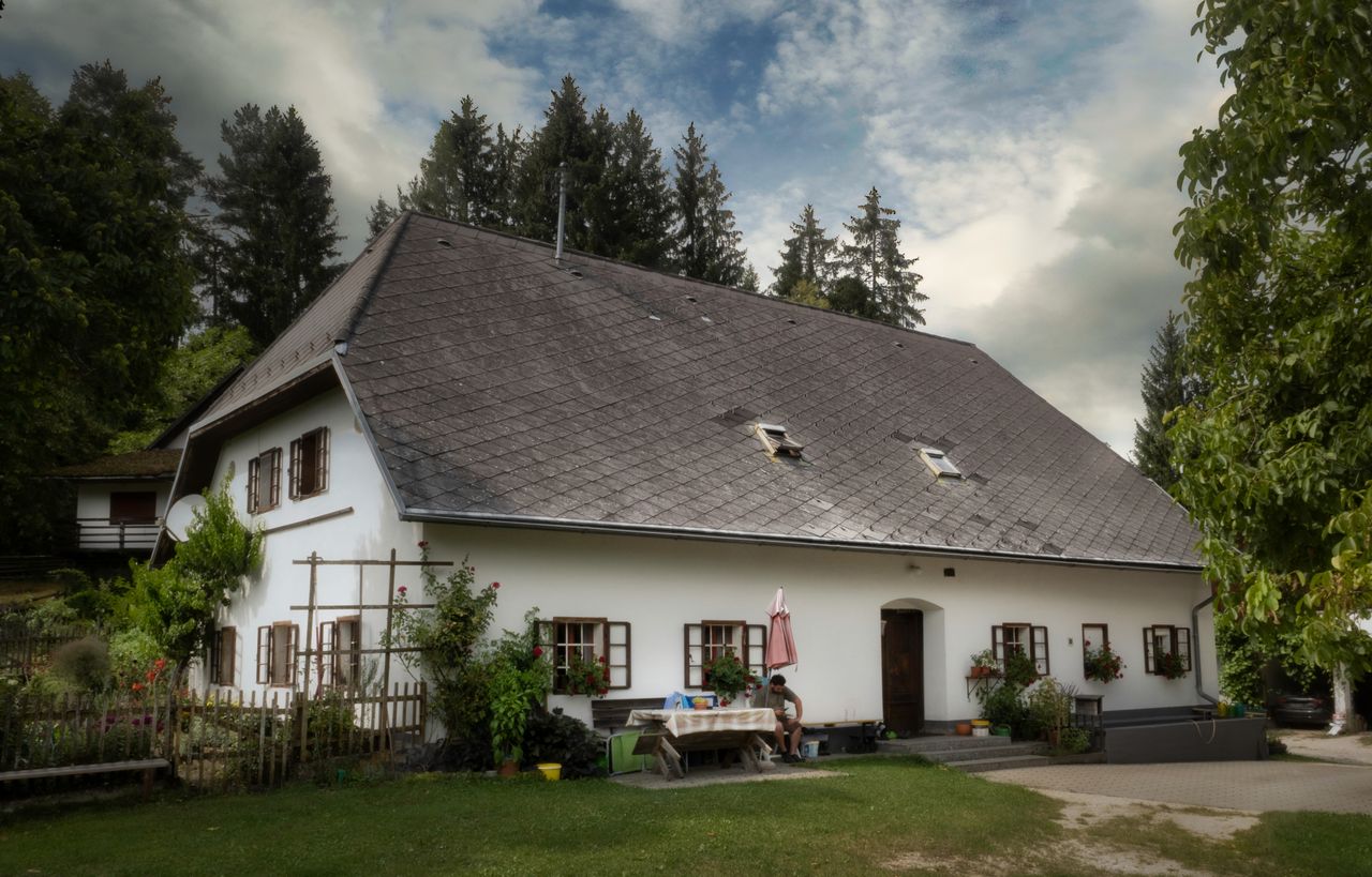 Traditional vintage-style house in Klagenfurt am Wörthersee, surrounded by lush greenery and picturesque skies.