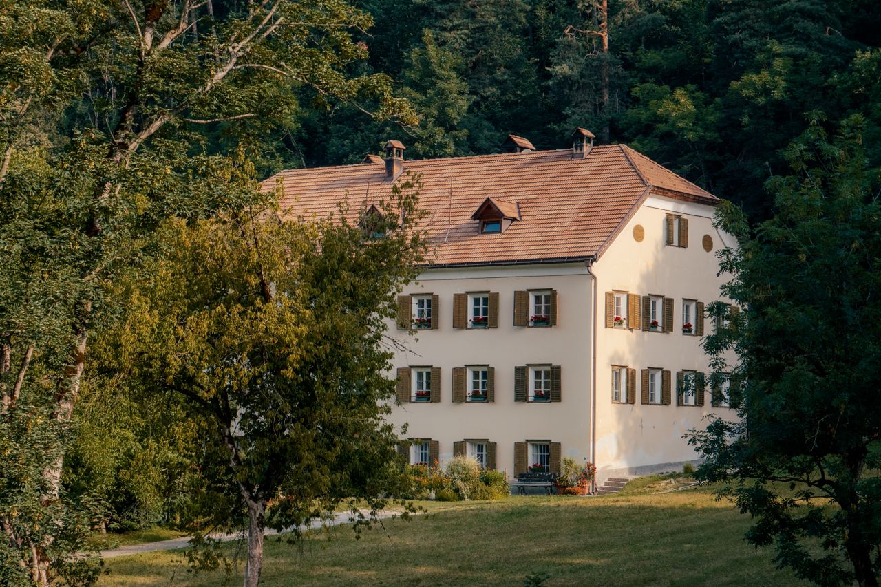 Picturesque country house amidst lush green trees in a serene setting.
